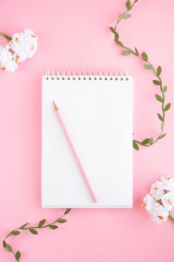 Defter, beyaz çarşaf, kalem, çiçekler. Pembe arka plan