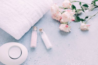 Spa ve vücut bakım ürünleri. Aromatik gül banyosu Deniz Tuzu, havlu, krem, gri arka plan üzerinde çiçek. Güzellik cilt bakımı. Spa tedavisi