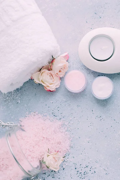 Spa ve vücut bakım ürünleri. Aromatik gül banyosu Deniz Tuzu, havlu, krem, gri arka plan üzerinde çiçek. Güzellik cilt bakımı. Spa tedavisi