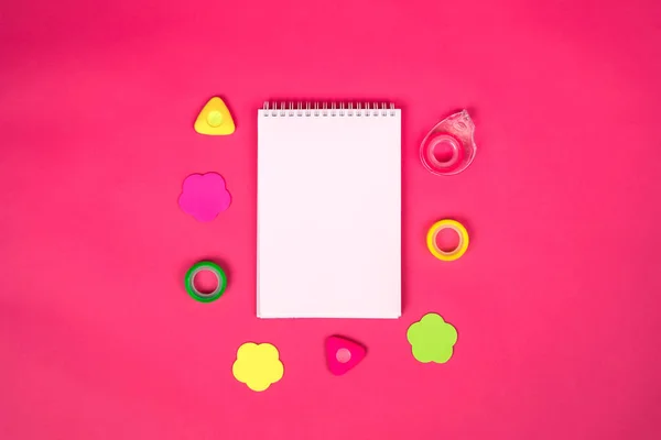 Pembe arka planda farklı okul malzemelerine sahip beyaz defter..