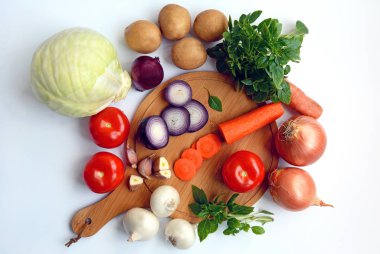 Beyaz bir arka planda patates, domates, lahana, soğan, havuç, sarımsak ve Yeşiller düzeni, üst görünüm.