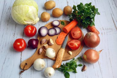 Hafif ahşap arka planda patates, domates, lahana, soğan, havuç, sarımsak ve Yeşiller düzeni.