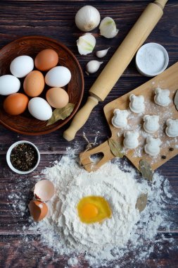 Tahta üzerinde yapılan köfte, un, plaka üzerinde yumurta, haddeleme pin, soğan, biber ve defne koyu ahşap arka planda yaprakları, üst görünüm.