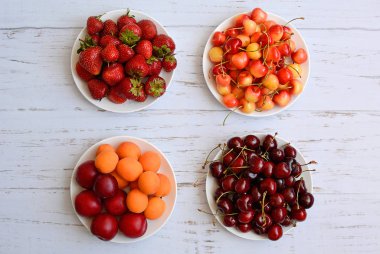 Farklı yaz meyveleri dört beyaz tabak, üst görünümü yalan.