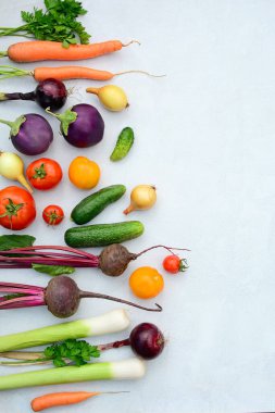Hafif arka planda taze mevsimlik sebzelerin dikey yerleşimi, üst manzara. Metin için kenar boşluk.