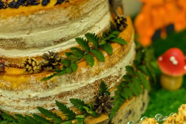 Çıplak kek ve beyaz krema ve yeşil eğrelti otu ile pasta bir parça yakın çekim. Bu günlük ev üzerinde, bir oyuncak mantar ve tatlılar yanında duruyor.