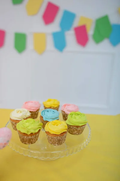 Beautiful multi-colored cupcakes. The room is decorated with bright decor. Close-up.