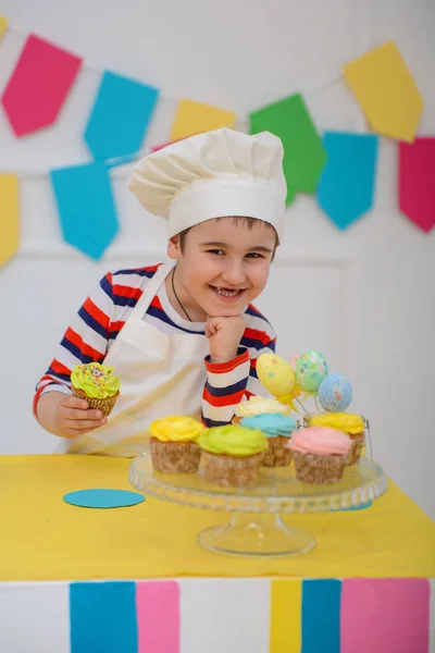 Boy Smiles Looks Camera Holds Easter Cupcake Dressed Chef Hat — Stock Photo, Image