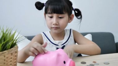4k küçük Asyalı kız koyarak para sikke kumbara ahşap tablo, içine gelecek için kaydetmek.