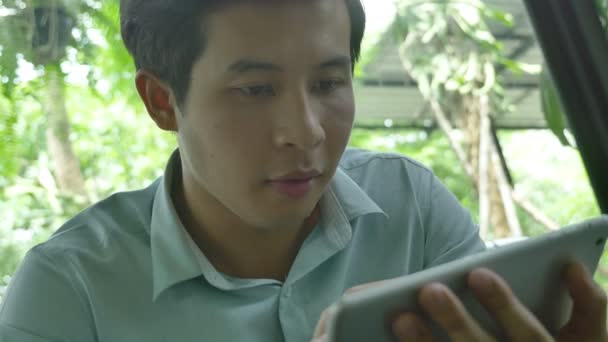 Asiatisk Ung Man Sitter Soffa Och Använder Tabletpc Kan Panorera — Stockvideo