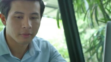 4k: dizüstü bilgisayar kullanarak ve kahve içme genç Asya iş adamı