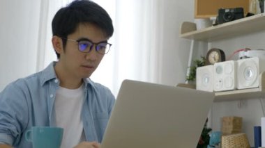 4k Genç Asyalı işadamı ofiste dizüstü bilgisayar üzerinde çalışan, yorgun duygu ve baş ağrısı olan