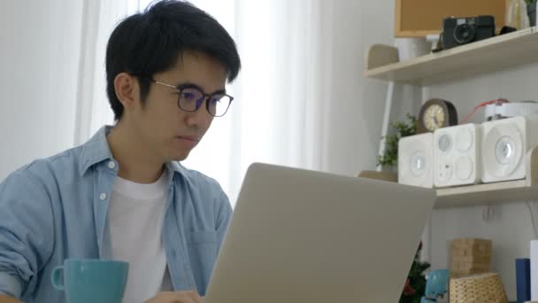 若いアジアのビジネスマンは オフィスでラップトップに取り組んで 疲れを感じ 頭痛を感じています — ストック動画