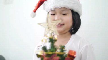 4k: mutlu güzel Asyalı kız Noel ağacı ve gösteren üzerinde süs hep birlikte koyarak