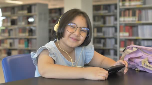 Asian Student Słuchania Muzyki Przez Słuchawki Szkolnej Bibliotece Powiększyć Strzał — Wideo stockowe