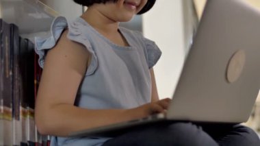 ilham için okul kitaplığında veri aramak için dizüstü bilgisayar kullanan 4k Asya öğrenci, çekim Tilt