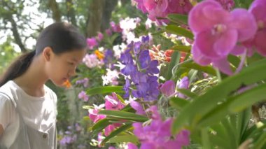 Güneşli bir gün yaz bahçesinde çiçeklenme çiçekler zevk mutlu Asyalı kız, yavaş hareket çekim
