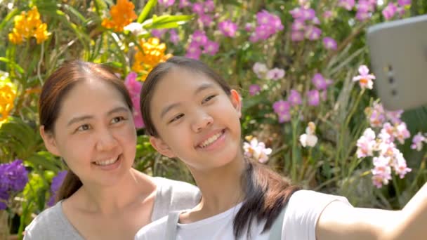 快乐的亚洲女孩和母亲享受盛开的花朵 一起拍照 慢动作拍摄 — 图库视频影像