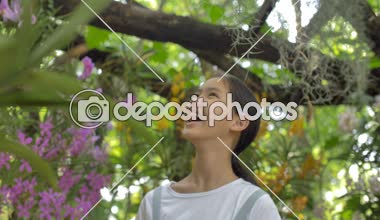 Güneşli bir gün yaz bahçesinde çiçeklenme çiçekler zevk mutlu Asyalı kız, yavaş hareket çekim