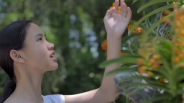 Güneşli bir gün yaz bahçesinde çiçeklenme çiçekler zevk mutlu Asyalı kız, yavaş hareket çekim