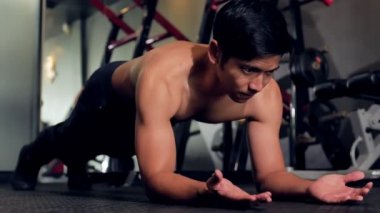 Genç Asyalı atlet eğitim kas vücut geliştirmespor salonunda plank egzersiz yapıyor, 4k 60fps