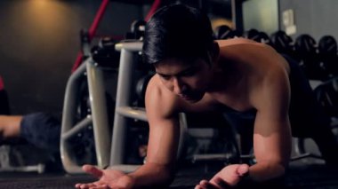 Genç Asyalı atlet eğitim kas vücut geliştirmespor salonunda plank egzersiz yapıyor, 4k 60fps