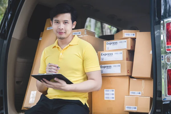 Young Asian Delivery man checking list of package boxes