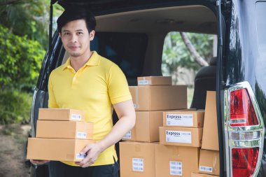 Sarı üniformalı genç Asyalı Teslimatçı, paket kutuları tutan