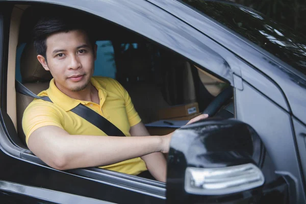Junger asiatischer Zusteller fährt Lieferwagen zur Paketzustellung Stockbild