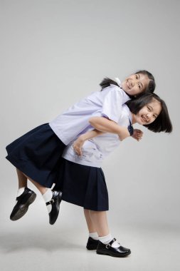 Mutlu gülümseyen küçük asya lı öğrenciler gri bac birlikte oynuyor