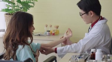 Asyalı doktor yaralı kolun durumunu dikkatlice kontrol ediyor, 50 fp.