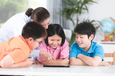 Asyalı öğretmen ve üç çocuklar kendilerini dijital tablet kullanma eğlenceli