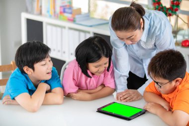 Asyalı öğretmen ve üç çocuklar kendilerini dijital tablet kullanma eğlenceli