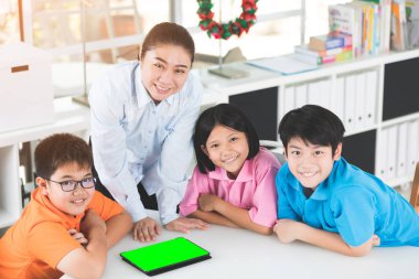 Asyalı öğretmen ve üç çocuklar kendilerini dijital tablet kullanma eğlenceli