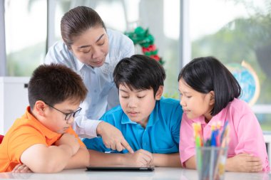 Asyalı öğretmen ve üç çocuklar kendilerini dijital tablet kullanma eğlenceli kapat