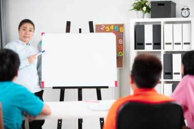 Genç Asyalı öğretmen sormak soru sınıf ile blabk beyaz tahta genç çocuklarda.