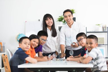 Neşeli erkek öğretmen açıklayan bir şeyler bir grup, Genç öğrenciler içinde sınıf.