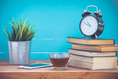 Kitap ve ahşap arka plan üzerinde saat ile çay