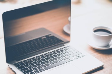 Beyaz fincan kahve ve ahşap masa üstünde laptop. iş kavramı.
