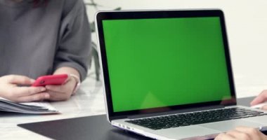 Asyalı kadın ofis çalışanı vasıl onun okul sırası bir Mock-up yeşil ekran dizüstü bilgisayarda çalışır. Omuz görüntüleri. Yaratıcı Office Evening.Dolly sağdan sola
