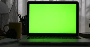 Yeşil ekran ile dizüstü bilgisayar. Karanlık ofisi. Dolly soldan sağa doğru. Kendi resim veya video koymak için mükemmel.