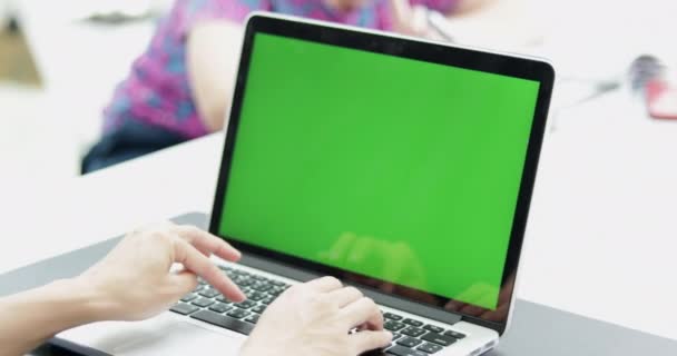 自分のデスクトップでアジア女性会社員は モックアップの緑色の画面のノート パソコンで動作します 肩の映像 右から左への創造的なオフィス Evening Dolly — ストック動画