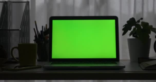 带绿色屏幕的笔记本电脑 黑暗的办公室 多莉进来 完美地放置自己的图像或视频 — 图库视频影像