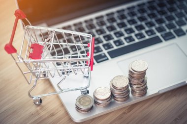 Sikke laptop ve çalışma alanı kullanarak evdekilerle online alışveriş veya teknoloji arka plan kavramları pazarlama olarak, ahşap masa üzerinde küçük alışveriş sepeti içerir.