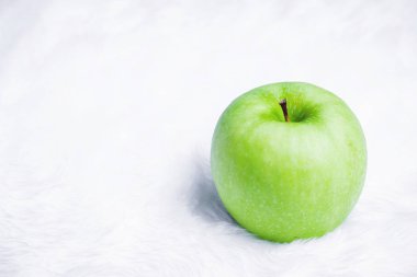 Beyaz halı üzerinde yeşil elma.