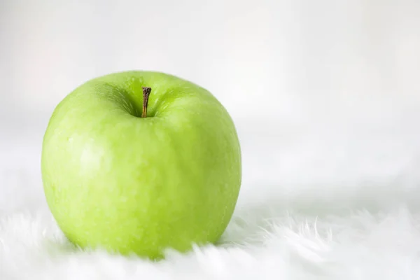 Green apple on white carpet with copy space .