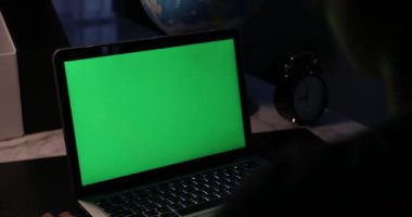 Yazarak ve bilgisayarda izlerken omuz görünümü üzerinde. Yeşil ekran teknolojisi kullanılıyor. Chroma anahtar laptop.