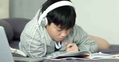 Genç Asyalı Genç öğrenci dinle müzik ve evde, ödev yapmak için Dolly ateş.