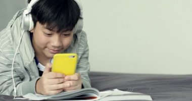 Genç Asyalı Genç öğrenci dinle müzik ve evde, ödev yapmak için Dolly ateş.