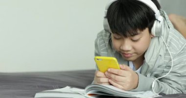 Genç Asyalı Genç öğrenci dinle müzik ve evde, ödev yapmak için Dolly ateş.